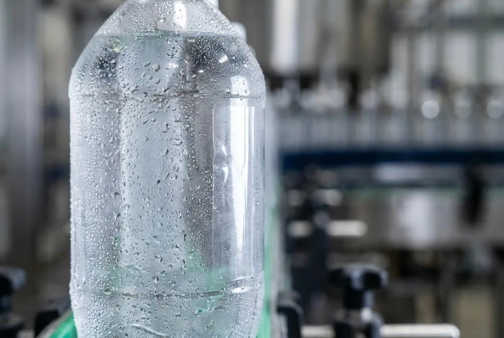 Clear Label On A Cold Fill Pet Beverage Bottle Showing No Tunneling On A High Speed Bottling Line Conveyor.