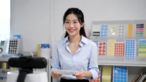 Professional Project Consultant In A Bright Office Showing A Physical Label Proof To A Remote Client During A High Definition Video Call.