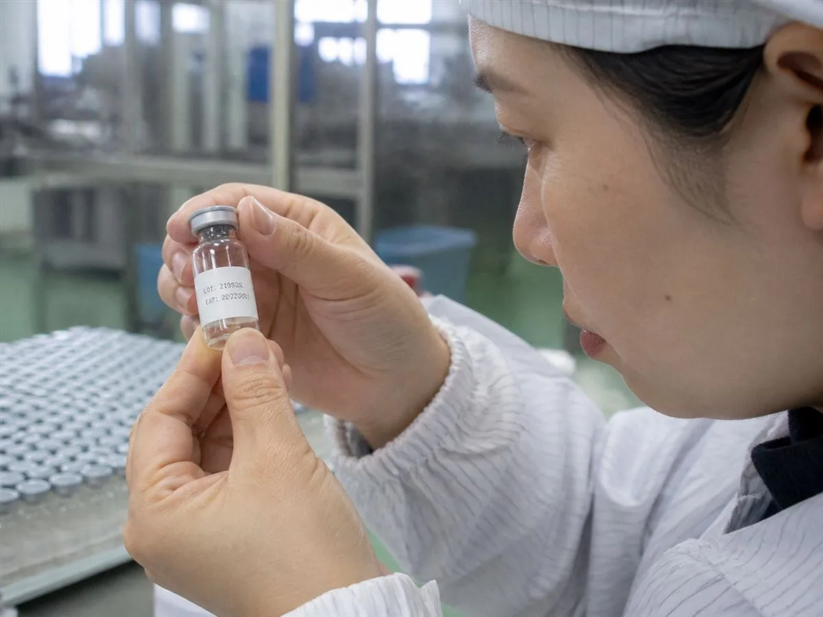Close-up of a tightly wrapped vial label with no edge lift, checked by a QC inspector