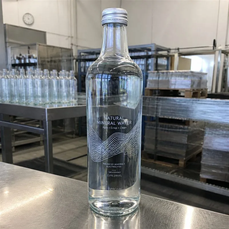Glass water bottle with clear no-label-look film showing water through the design