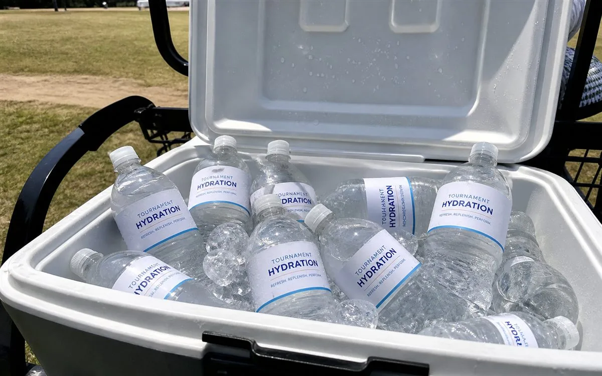 Golf cart cooler box with custom labeled water bottles at outdoor event