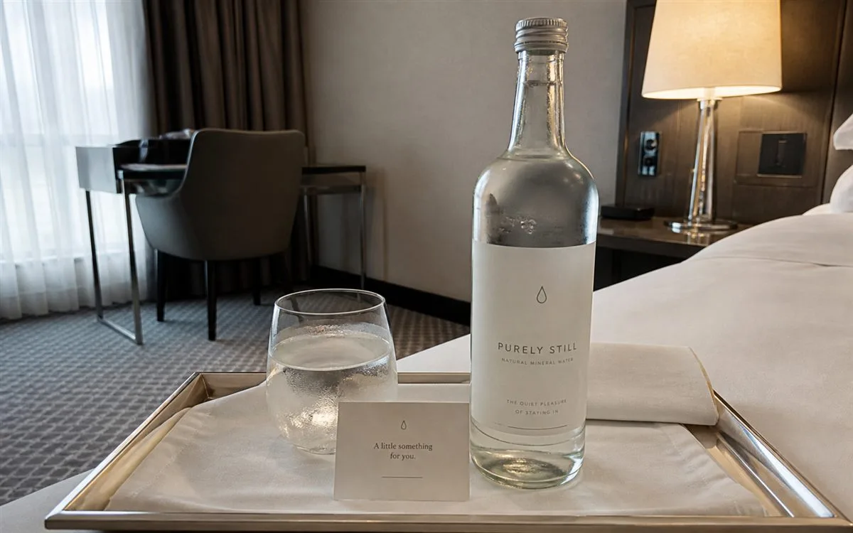 Hotel room tray with glass water bottle and premium label
